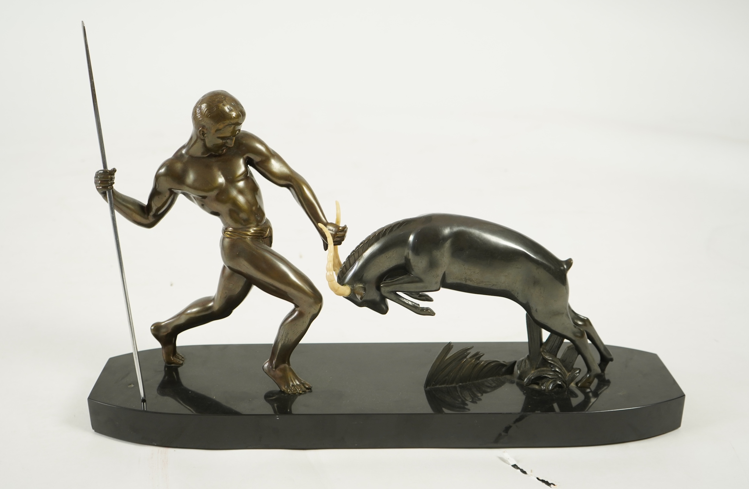 Attributed to Zoltan Kovasz (Romanian, 1883-1952), a bronzed spelter male hunter holding a chromed spear, with springbok, on a polished slate base
